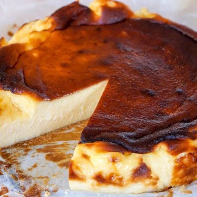 Traditional wood-fired Basque cheesecake with a caramelized golden-brown crust, styled on parchment paper.